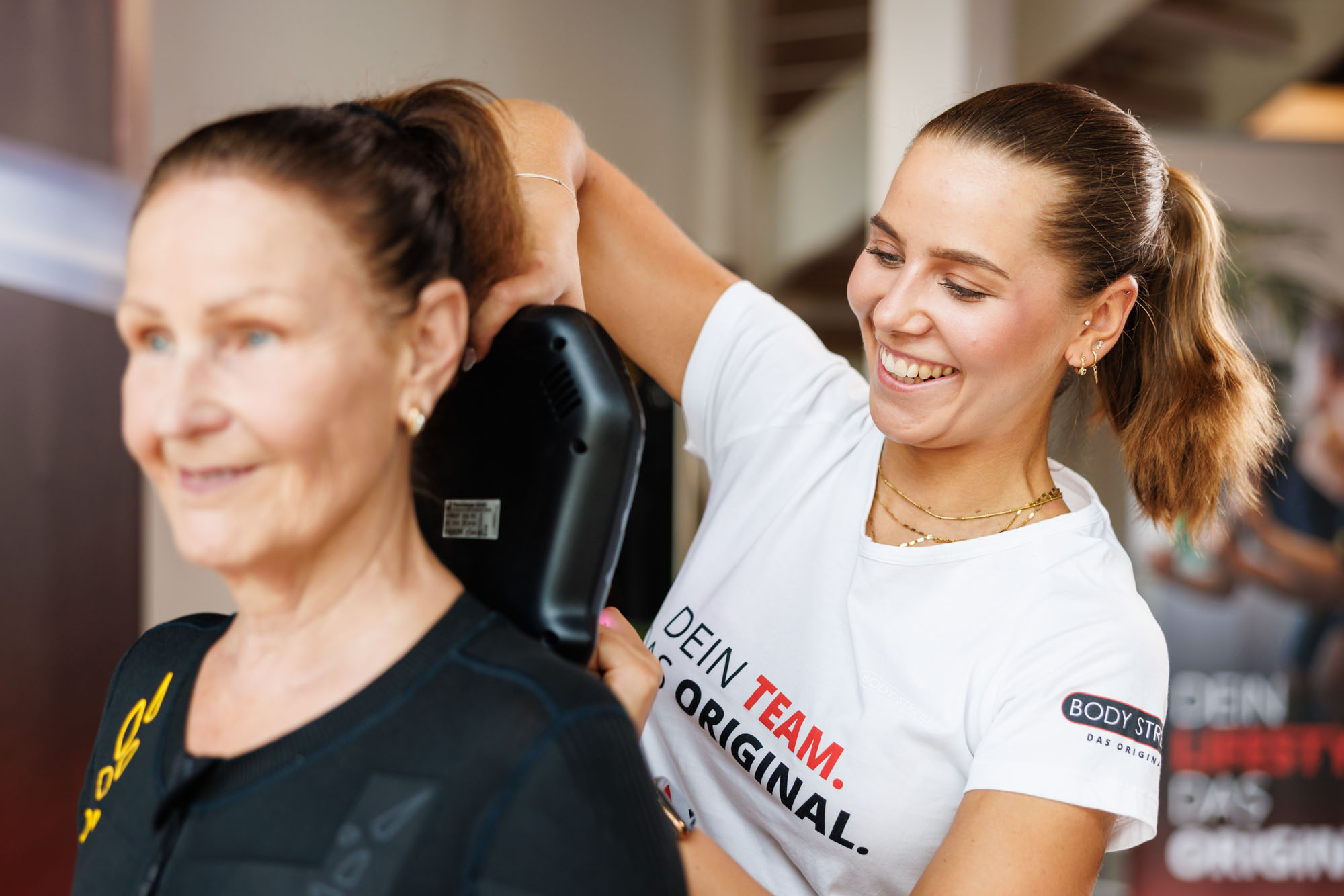 Trainerin im EMS-Studio lacht gemeinsam mit einer Kundin während des Trainings